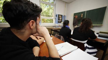 Ein Schüler sitzt in der Klasse und stützt seinen Kopf auf den Arm.