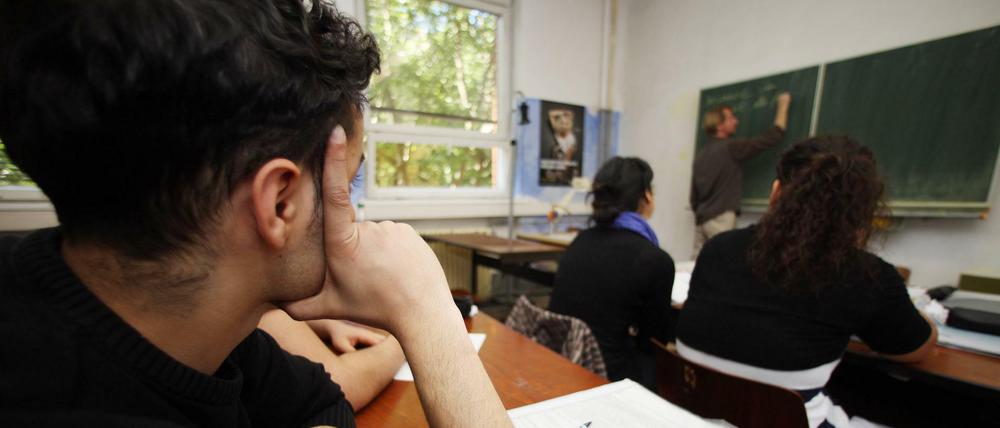 Ein Schüler sitzt in der Klasse und stützt seinen Kopf auf den Arm.