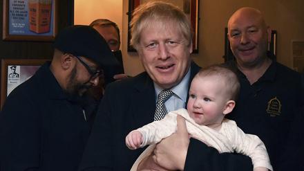 Boris Johnson hält ein Baby auf dem Arm während er sich mit Militärveteranen trifft.