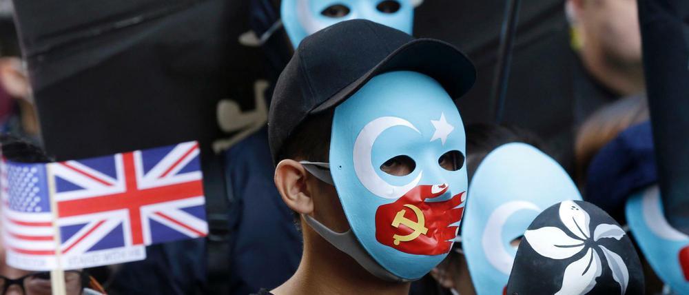 Demonstranten In Hongkong tragen Masken, auf denen eine rote Hand mit chinesischer Flagge ihnen den Mund zuhält.