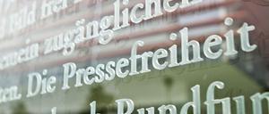 Das Wort Pressefreiheit in einem Ausschnitt des Artikels 5 des Grundgesetzes auf einer Glasscheibe am Außenhof eines Parlamentsgebäudes in Berlin.
