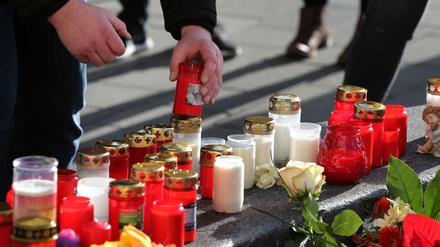 Ein Mann platziert ein Grablicht an einem Rondell am Königsplatz. Ein Feuerwehrmann war am Freitagabend (06.12.2019) hier so schwer verletzt worden, dass er noch vor Ort starb.