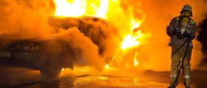 Feuerwehrleute löschen ein brennendes Auto (Symbolbild).