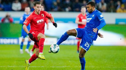 Hoffenheims Kevin Akpoguma (r) kommt vor Augsburgs Florian Niederlechner an den Ball. 