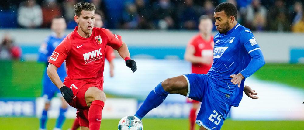 Hoffenheims Kevin Akpoguma (r) kommt vor Augsburgs Florian Niederlechner an den Ball. 