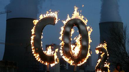Mit einem brennenden CO2-Zeichen demonstrieret Greenpeace vor dem Kohlekraftwerk Staudinger in Hanau. 