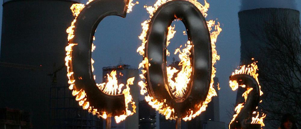Mit einem brennenden CO2-Zeichen demonstrieret Greenpeace vor dem Kohlekraftwerk Staudinger in Hanau.