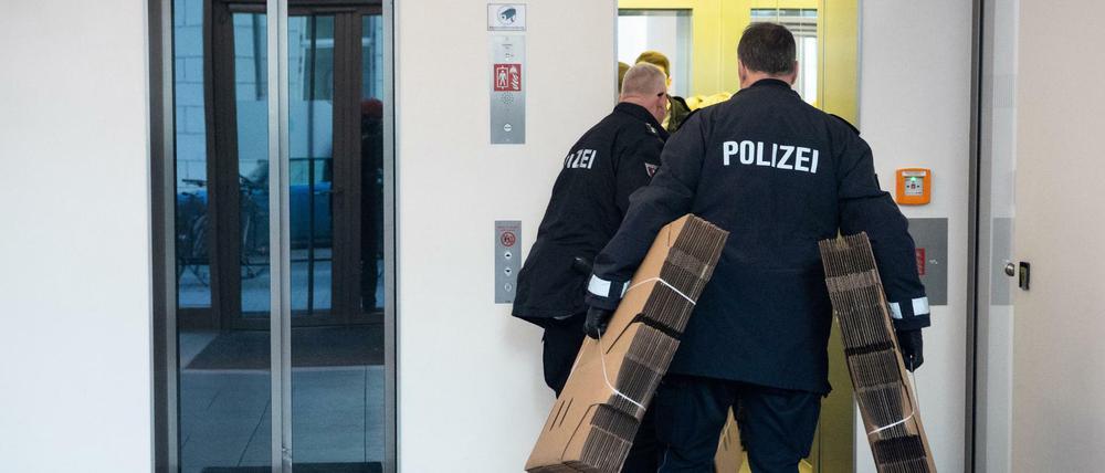 Polizeibeamte gehen in ein Bürogebäude, in dem sich eine Niederlassung eines Pharmaunternehmens befindet.