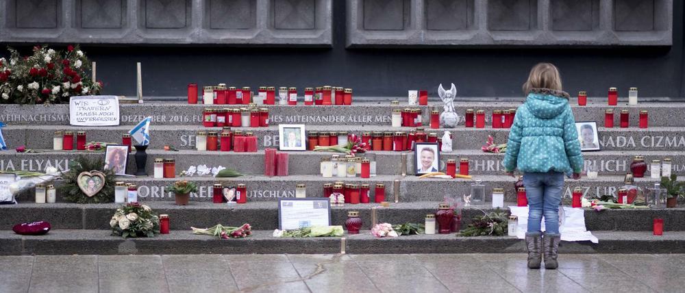 Ein Mädchen betrachtet Kerzen, Blumen und Andenken an der Gedenkstätte auf dem Breitscheidplatz. (Archivbild)