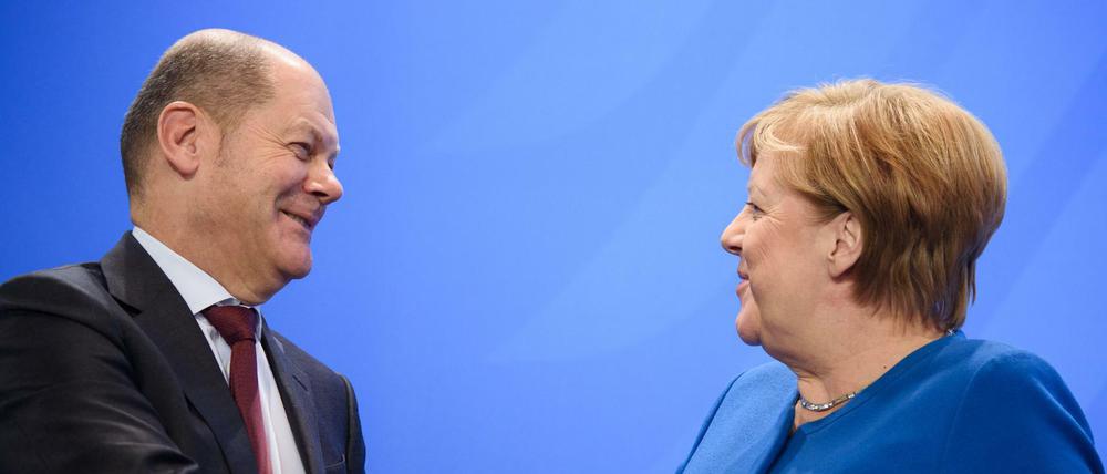 Olaf Scholz (SPD) und Angela Merkel (CDU) geben sich die Hand.
