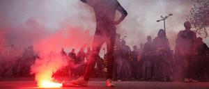 Ein Demonstrant in Lyon steht mit seinem rechten Fuß auf einer Leuchtrakete.