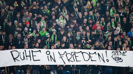 Fans des VfL Wolfsburg halten ein Plakat mit der Aufschrift "Ruhe in Frieden!". 