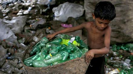 Siyam (10) sortiert in Dhaka (Bangladesch) Plastikflaschen in einer Recylingfabrik. 