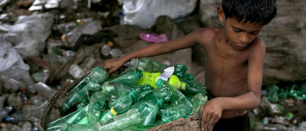 Siyam (10) sortiert in Dhaka (Bangladesch) Plastikflaschen in einer Recylingfabrik.
