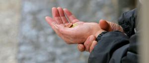 Eine Frau bittet Passanten um eine Spende.