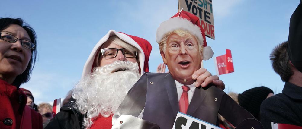 Eine als Weihnachtsmann verkleidete Labour-Unterstützerin hält eine Pappfigur des US-Präsidenten Trump