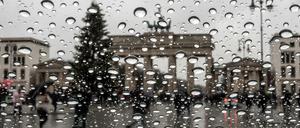 Viel zu warm für Schnee: Das Brandenburger Tor und ein Weihnachtsbaum stehen hinter der Scheibe eines Autofensters auf dem Regentropfen hängen.