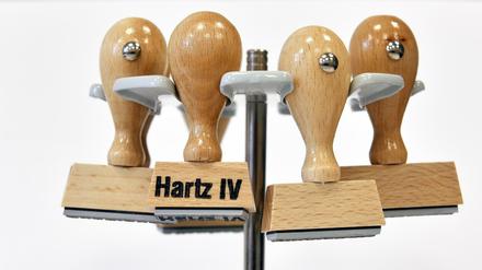Ein Stempel mit der Aufschrift Hartz IV hängt an einem Stempelträger.