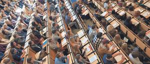 Studierende sitzen in einem Hörsaal, einige Plätze sind frei geblieben.