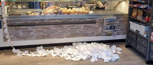Riesiger Papierverbrauch: Die gesammelten Kassenzettel von zwei Tagen liegen in einer Bäckerei auf dem Boden.