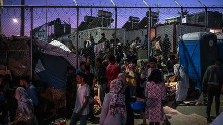 Migranten verlassen das Lager Moria durch ein Loch im Zaun auf der Insel Lesbos.