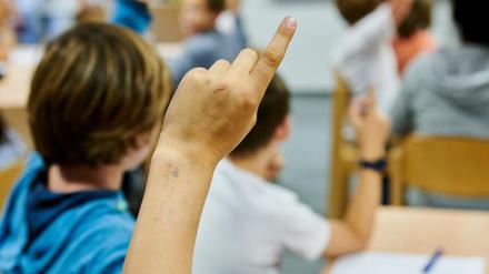 Ein Junge meldet sich in einer Schulklasse. 