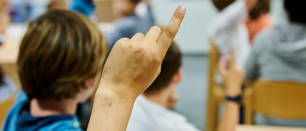 Ein Junge meldet sich in einer Schulklasse. 
