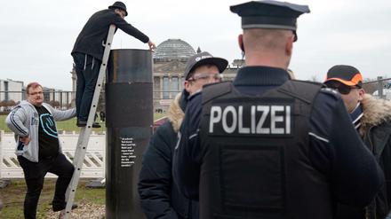Der jüdische Autor Eliyah Havemann (2.v.l.) befestigt eine zuvor abmontierte Stahlplatte wieder auf der umstrittene Stahlsäule des Künstlerkollektivs "Zentrum für politische Schönheit". Die Polizei hatte den Abbau gestoppt.