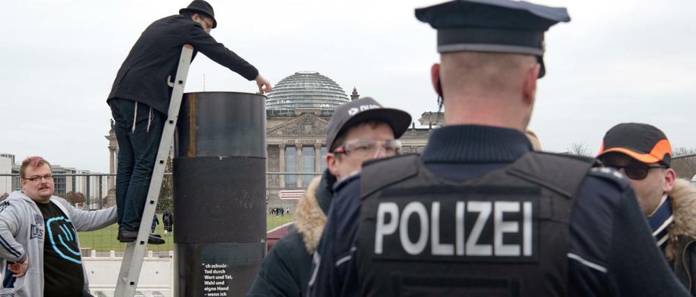 Der jüdische Autor Eliyah Havemann (2.v.l.) befestigt eine zuvor abmontierte Stahlplatte wieder auf der umstrittene Stahlsäule des Künstlerkollektivs "Zentrum für politische Schönheit". Die Polizei hatte den Abbau gestoppt.