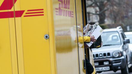 Ein DHL-Paketzusteller verlässt mit mehreren Sendungen sein Fahrzeug im Paulusviertel in Halle.