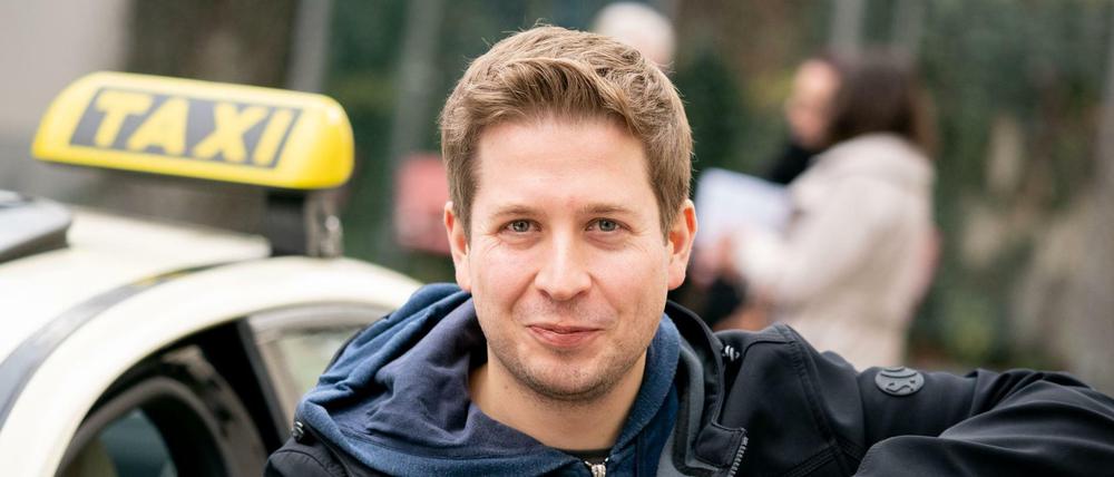 Kevin Kühnert, stellvertretender Bundesvorsitzender der SPD, steht nach der Besichtigung der Taxizentrale von Taxi Berlin an einem Taxi. 