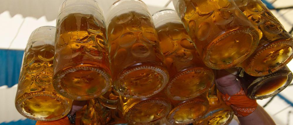 Ein Kellner trägt auf einem Volksfest Bierkrüge.