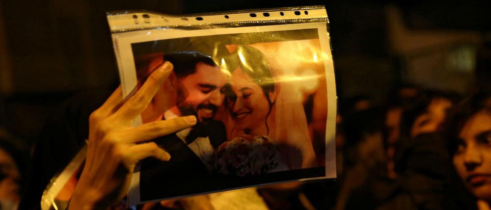 Eine Demonstrantin zeigt das Foto eines frisch verheirateten Paares, das beim Absturz starb.