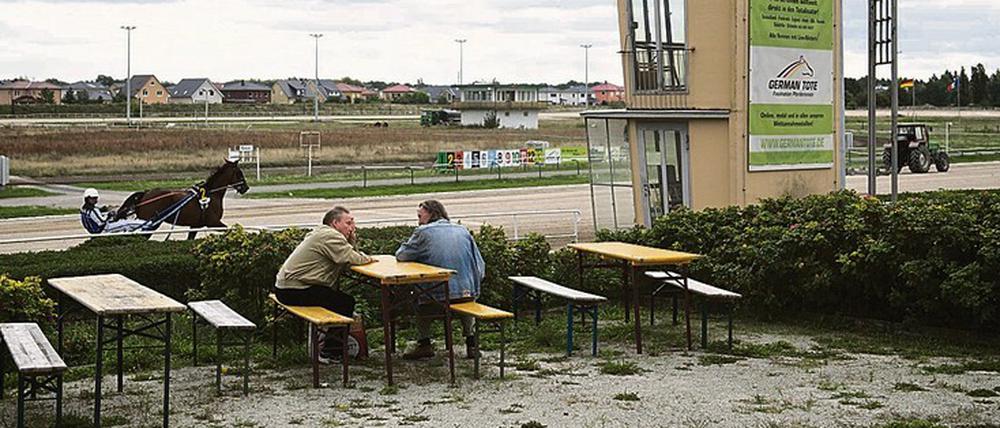 Kulisse aus einer anderen Zeit. Zur Trabrennbahn Karlshorst gehört ein sandiger Rundkurs, ein wackliger Zielturm, eine Fressbude aus Holz und eine Tribüne.