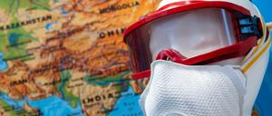 Ein Mundschutz und eine Schutzbrille sind in einem Besprechungszimmer der Task-Force Infektiologie am Flughafen München vor einer Landkarte zu sehen.