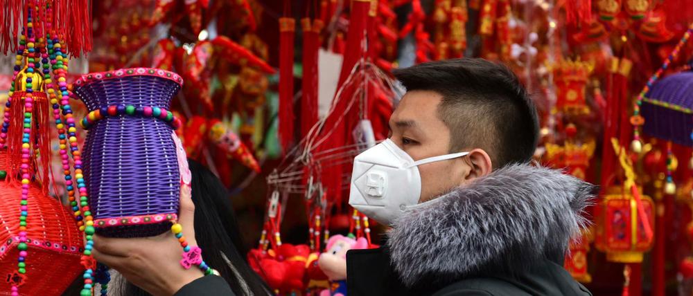 Ein Mann trägt eine Gesichtsmaske, während er auf einem Markt in Fuyang für das bevorstehende chinesische Neujahrsfest zum Jahr der Ratte einkauft.