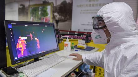 Ein Sicherheitsmitarbeiter kontrolliert die Körpertemperatur der Passagiere am Sanya Phoenix International Airport in China. 