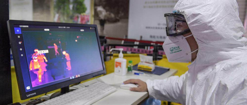 Ein Sicherheitsmitarbeiter kontrolliert die Körpertemperatur der Passagiere am Sanya Phoenix International Airport in China. 