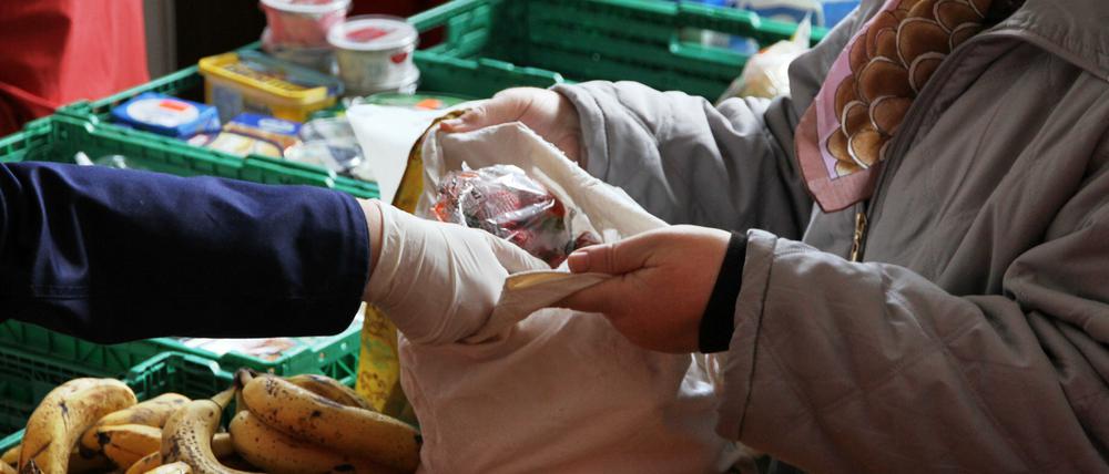 Eine Mitarbeiterin der Berliner Tafeln verteilt Obst an Bedürftige.