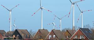 Windkrafträder stehen dicht hinter einer Wohnsiedlung.