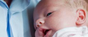 Ein Vater mit seinem Neugeborenen. (Symbolbild)