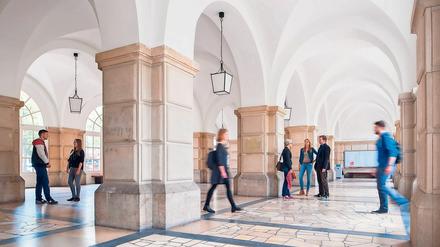 Studierende stehen und gehen im Foyer eines Hochschulgebäudes.