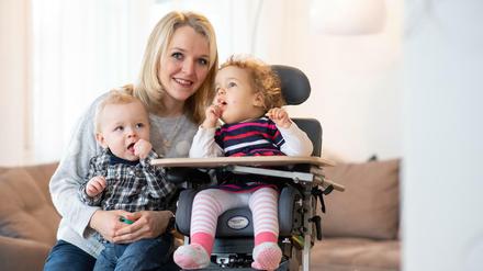 Alexa, die an spinaler Muskelatrophie (SMA Typ 1) leidet, sitzt neben Mutter Margarete und Bruder Theo.