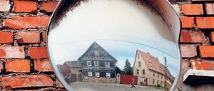 Kennste deine, kennste alle. Der verwitterte Verkehrsspiegel zeigt eine Dorfstraße in Thüringen als Zerrbild provinzieller Tristesse.