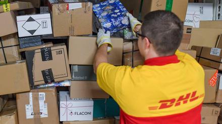 Ein DHL-Mitarbeiter stapelt Sendungen in einen Lkw.
