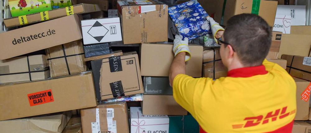 Ein DHL-Mitarbeiter stapelt Sendungen in einen Lkw.