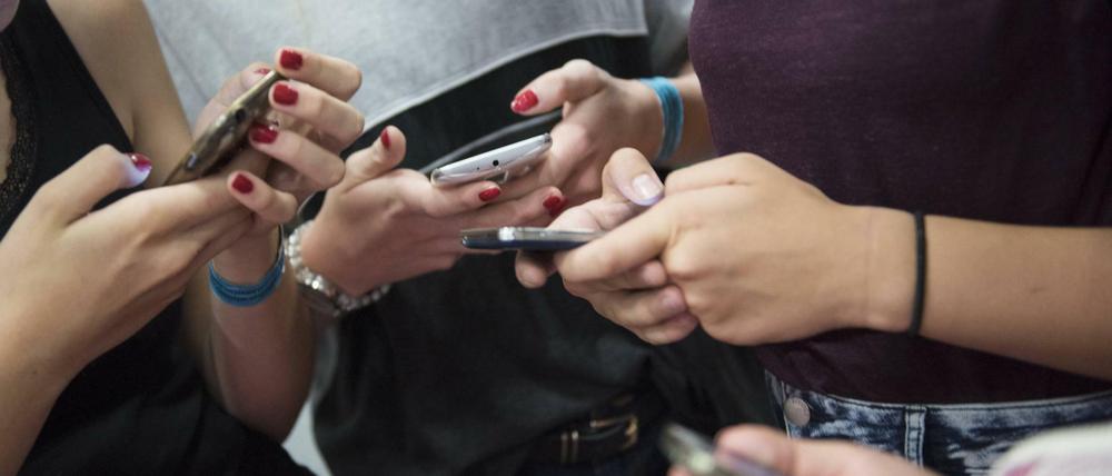 Ein Gruppe von Mädchen tippt auf ihren Smartphones herum.