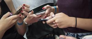 Ein Gruppe von Mädchen tippt auf ihren Smartphones herum.