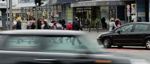 Ein Auto fährt schnell über die Kreuzung Schloßstraße / Grunewaldstraße in Steglitz, im Hintergrund weitere Autos und Fußgänger.
