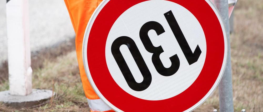 Ein Straßenwärter hält an der Autobahn A24 ein Verkehrsschild mit der Geschwindigkeitsangabe 130 Stundenkilometer.